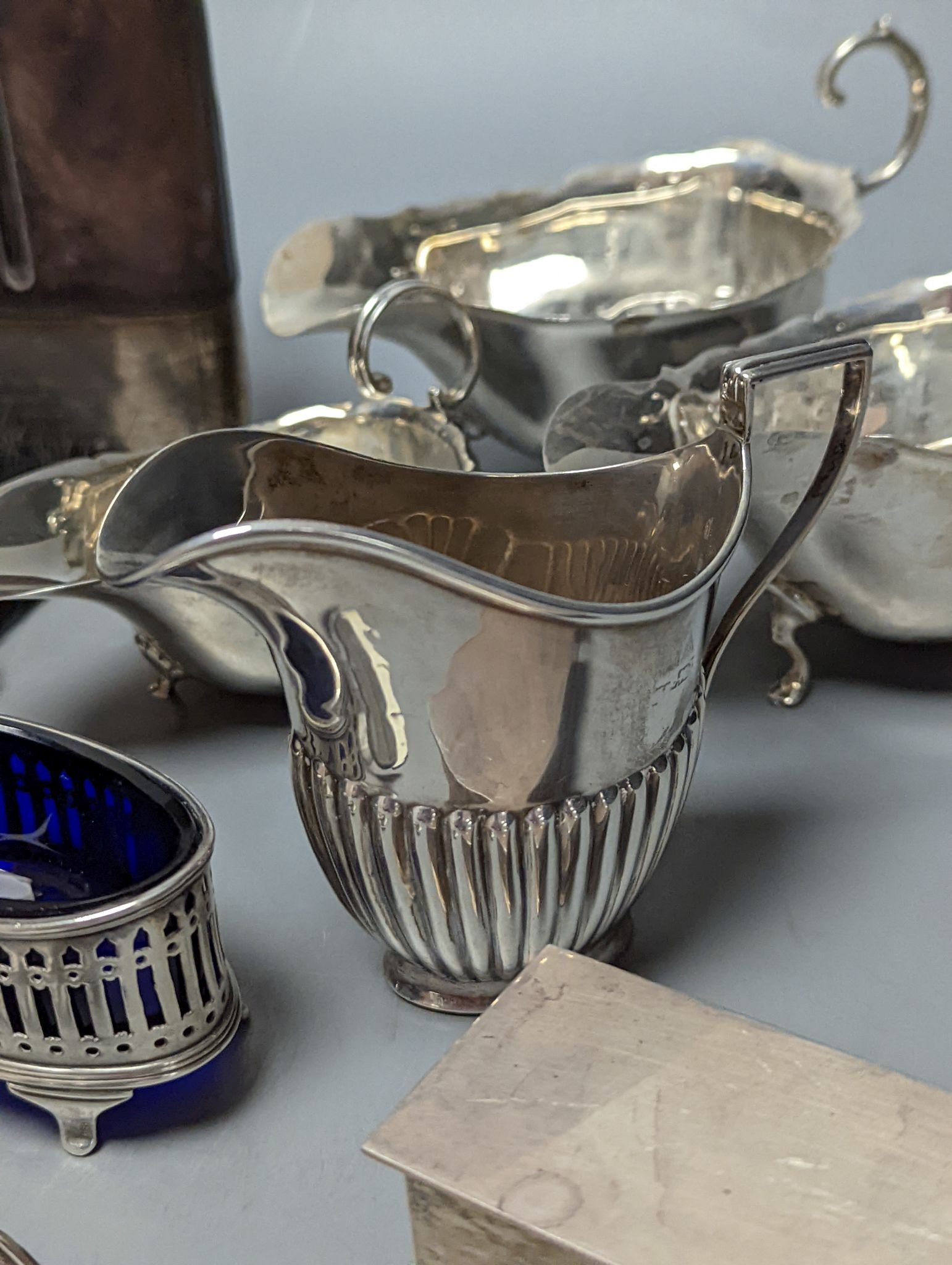 A group of assorted silver items including George V silver mounted hip flask(bruise), a pair of silver sauceboats(a.f.) one other sauceboat, sterling box, two silver cream jugs, cigarette box, salt, sugar tongs, brush an